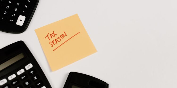 tax season written on post-it surrounded by calculators
